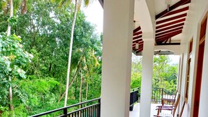A covered outdoor seating area with wooden benches and a black metal railing, overlooking a lush green landscape. - Wild Safari Nest Udawalawe  (Udawalawe)
