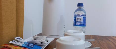 A table with a water bottle, a plate of snacks, and a white cup.