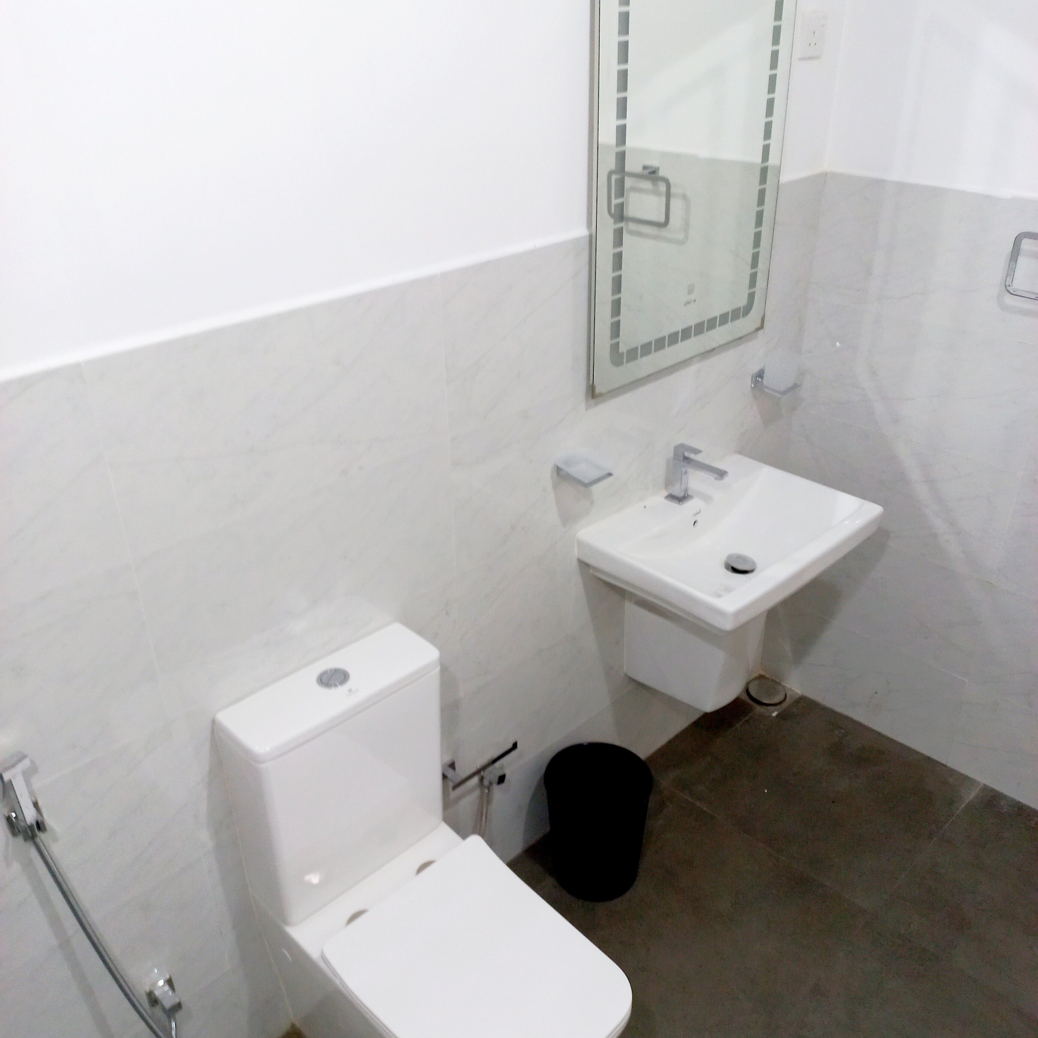 A bathroom with a toilet, sink, and mirror.