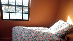 A single bed with a floral bedspread in a room with a window. - Lyn's Suite (Saint George)