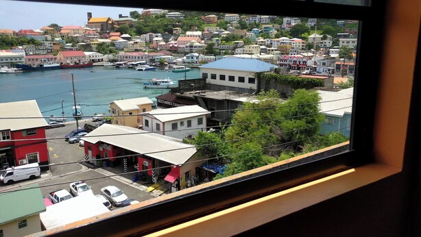 A coastal town with buildings along the waterfront, a marina with boats, and a clear view of the sea. - Lyn's Suite (Saint George)