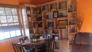 A cozy living room with a dining area, featuring a bookshelf, a television, and a comfortable seating arrangement. - Lyn's Suite (Saint George)
