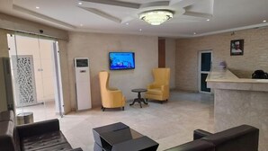 A modern lobby with leather sofas, a TV, and a reception desk.