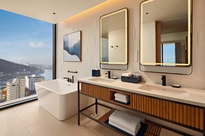 A modern bathroom with a large bathtub, dual sinks, and two mirrors.