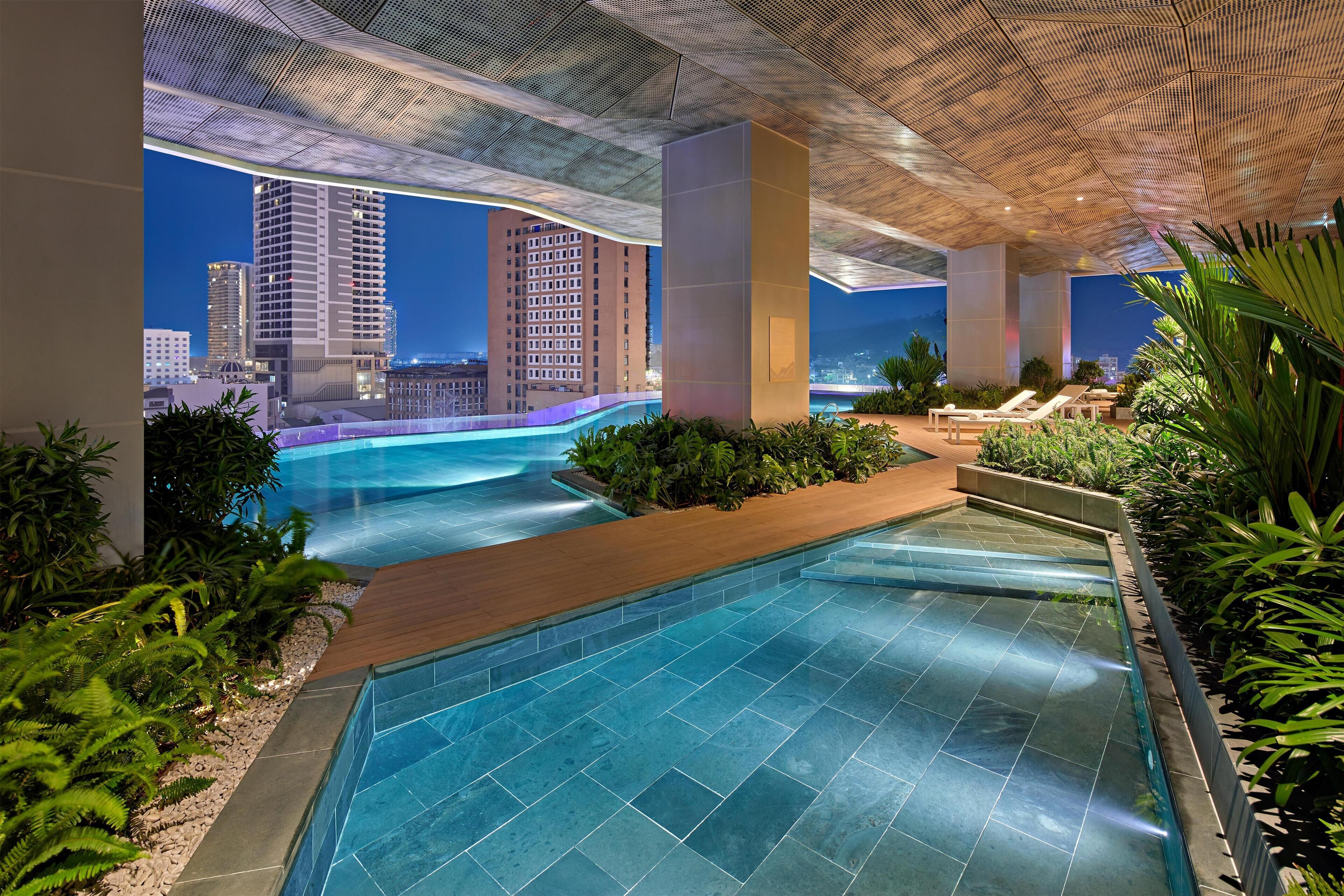 Een buitenzwembad, parasols bij het zwembad en ligstoelen