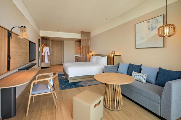 Una habitación de hotel moderna con cama, sofá, escritorio y televisor.