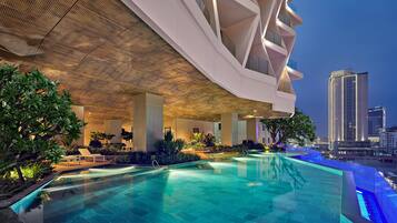 Una piscina al aire libre, sombrillas, sillones reclinables de piscina