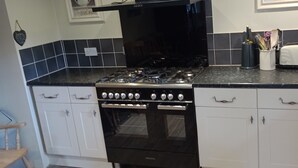 A kitchen with a black stove, white cabinets, and a toaster on the counter.