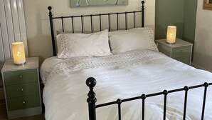 A bed with a black metal frame, white bedding, and two bedside tables with lamps. - Sygun Cottage 40 mins walk to Watkin Waterfalls, Snowdon (Beddgelert)