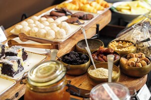 A buffet with various food items including cakes, fruits, nuts, and grains.