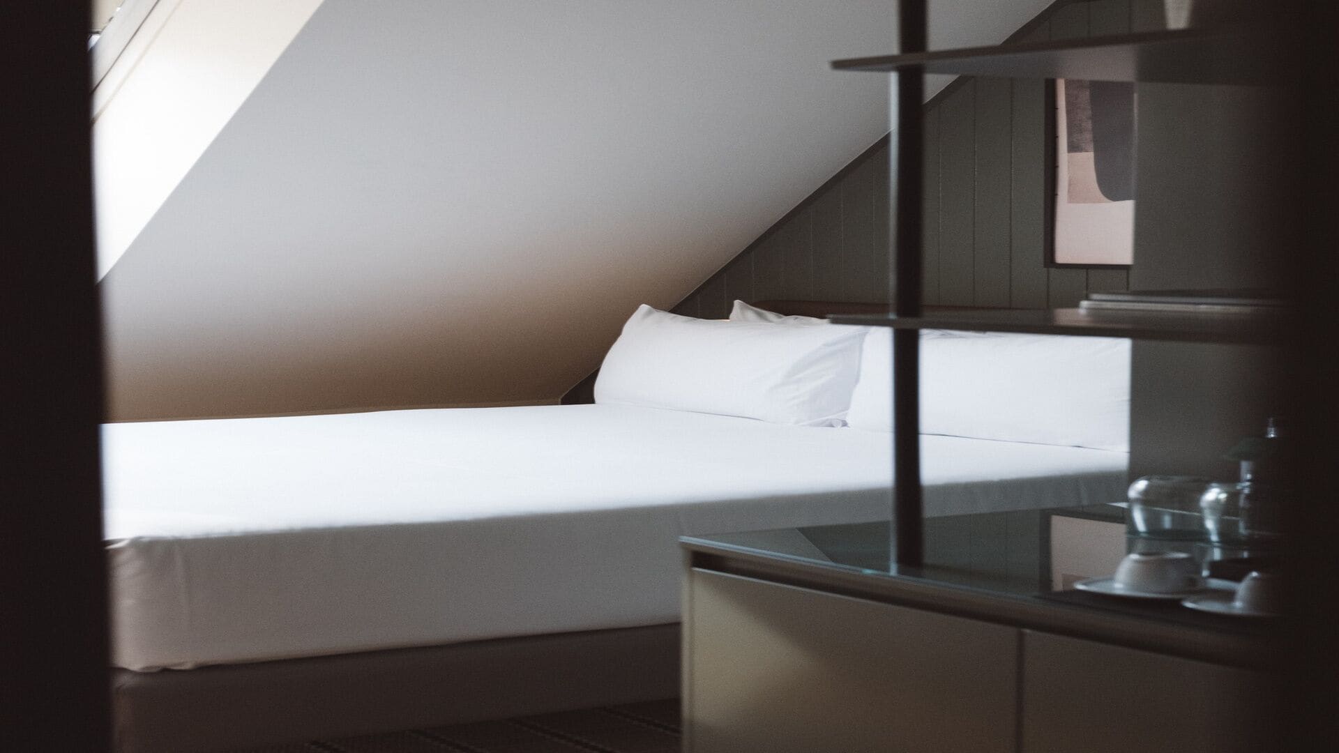 Quarto com uma cama, mesa de cabeceira e janela.
