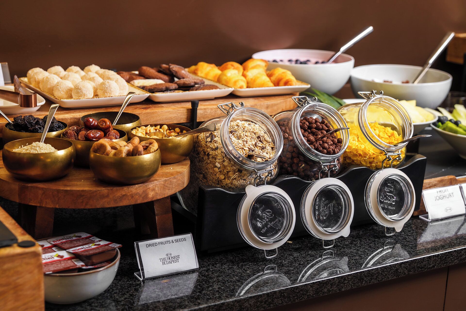 A buffet with various food items, including pastries, fruits, and nuts.