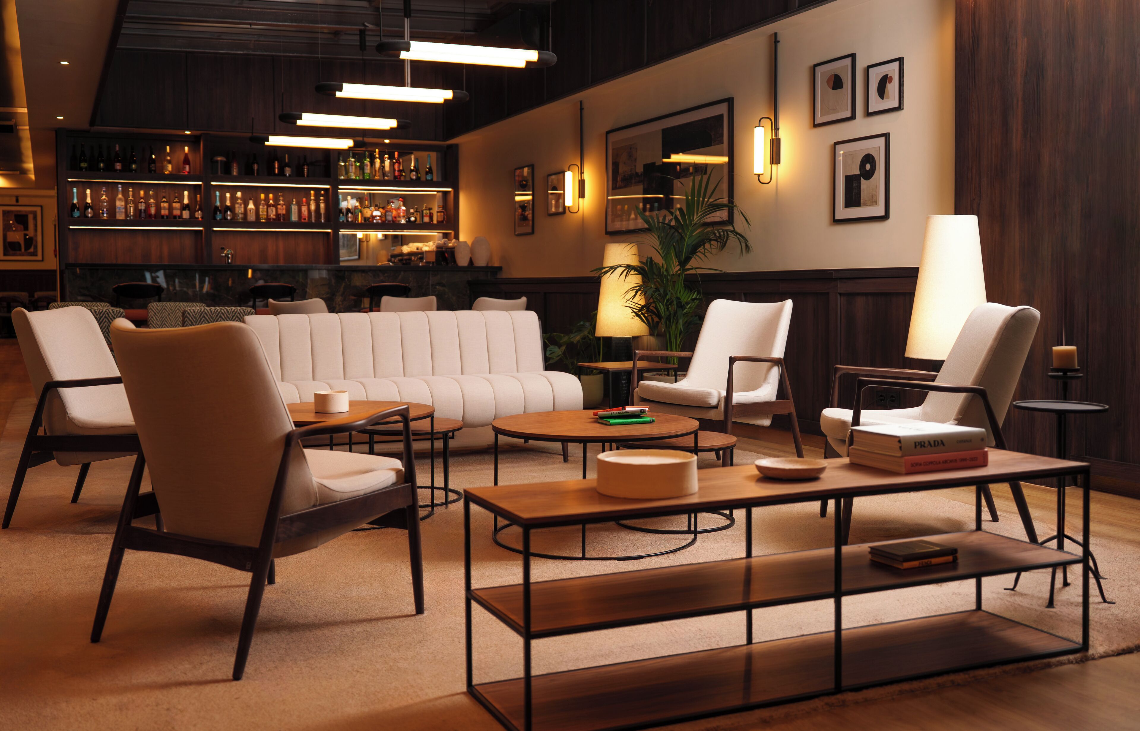 Un'area lounge moderna con divani in pelle, tavoli di legno e un bar con scaffali pieni di bottiglie.