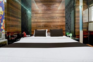 A large bed with a white and dark brown bedspread, flanked by two nightstands with lamps, in a room with a wooden wall and patterned wallpaper. - Modern Comfort Stays at Swarop Nagar Kanpur (Kanpur)