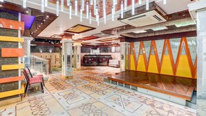 A modern hotel lobby with patterned flooring, a seating area, and a decorative wall with geometric shapes. - Modern Comfort Stays at Swarop Nagar Kanpur (Kanpur)