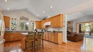 A spacious kitchen with wooden cabinets, a central island with bar stools, and a large window.