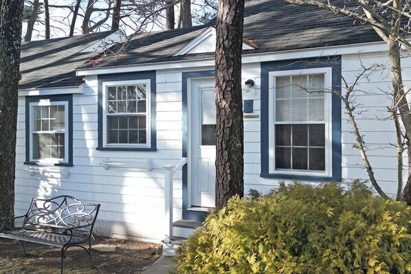 A two-story house with a front porch, a bench, and a well-maintained lawn.