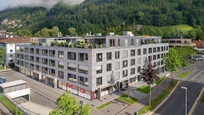 A modern building with multiple floors, large windows, and a flat roof.