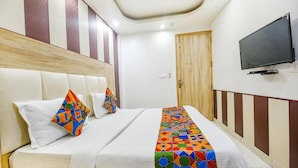 Une chambre d’hôtel avec un lit, des oreillers, une télévision et une porte.