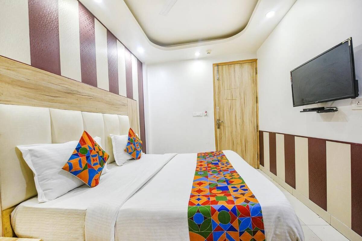 A hotel room with a bed, pillows, a TV, and a door.