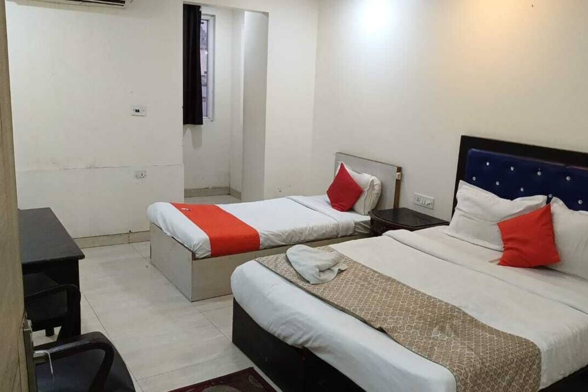 A hotel room with two beds, each with a headboard, a desk, and a chair.