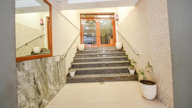 Un escalier aux murs de marbre, une porte en bois et des plantes en pot.