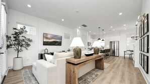 A modern kitchen with white cabinetry, a wooden dining table, and a built-in oven.
