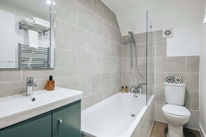 A modern bathroom with a white sink, a glass-enclosed shower, and a toilet with a patterned seat cover. - The Regency by nestor | 2BD LG Apartment (London)