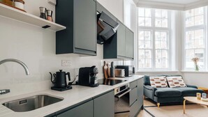 Et moderne køkken med mørke skabe, en rustfri stålvask og en kaffemaskine.