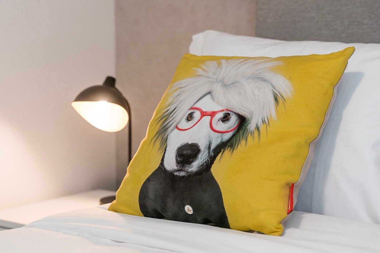 Almofada com ilustração de um cachorro em uma cama.