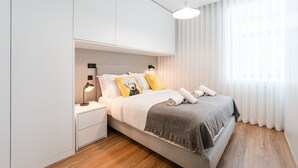 Et moderne soveværelse med seng, sengeborde og en hængende lampe.