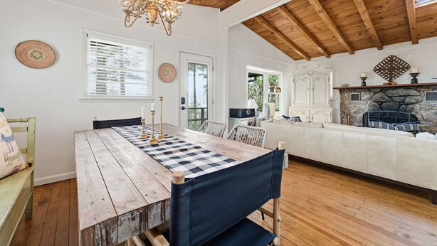 A wooden dining table with a checkered table runner, a chandelier, and a stone fireplace. - Highlands Close-to-Town Cabin, Pet-Friendly (Highlands)