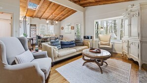 A spacious living room with a high wooden ceiling, a beige sofa with patterned cushions, a round coffee table, and a white cabinet. - Highlands Close-to-Town Cabin, Pet-Friendly (Highlands)