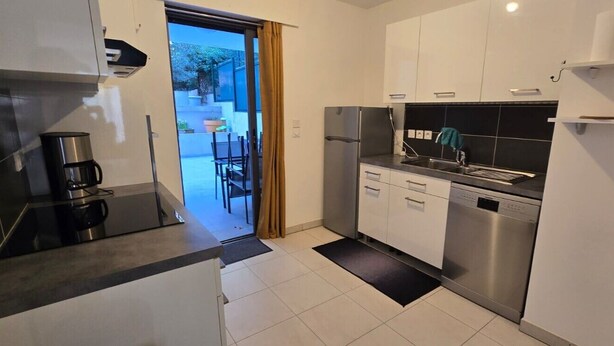 Una cocina moderna con armarios blancos, un refrigerador de acero inoxidable y un lavavajillas.