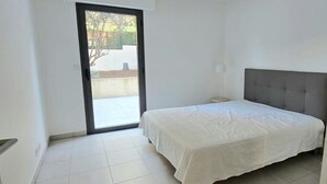 Un dormitorio con una cama, una mesita de noche, una ventana y una puerta que da a un balcón.