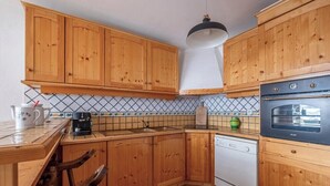 Una cocina con armarios de madera, lavavajillas blanco y horno negro.