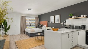 A modern hotel room with a bed, bedside table, and a small kitchen area. - Stylish De Waterkant Escape Pool andPrime Location (Cape Town)
