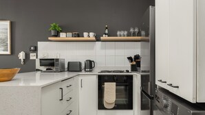 A modern kitchen with white cabinetry, a microwave, a kettle, and a built-in oven. - Stylish De Waterkant Escape Pool andPrime Location (Cape Town)