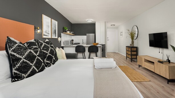 A modern hotel room with a bed, a desk, and a kitchenette. - Stylish De Waterkant Escape Pool andPrime Location (Cape Town)