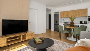 A modern living room with a flat-screen TV, wooden entertainment unit, and a round coffee table with books and a decorative item. - Ratanga Park Escape | Century City (Cape Town)
