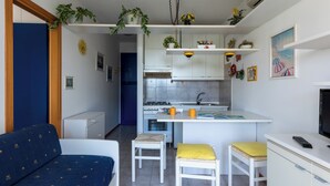A compact living space with a kitchenette, a dining area, and a sofa. - Great Apartment With Stunning Terrace in Bibione (San Michele al Tagliamento)