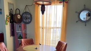 Un comedor con una mesa redonda y cuatro sillas, una lámpara colgante y una ventana con cortinas.