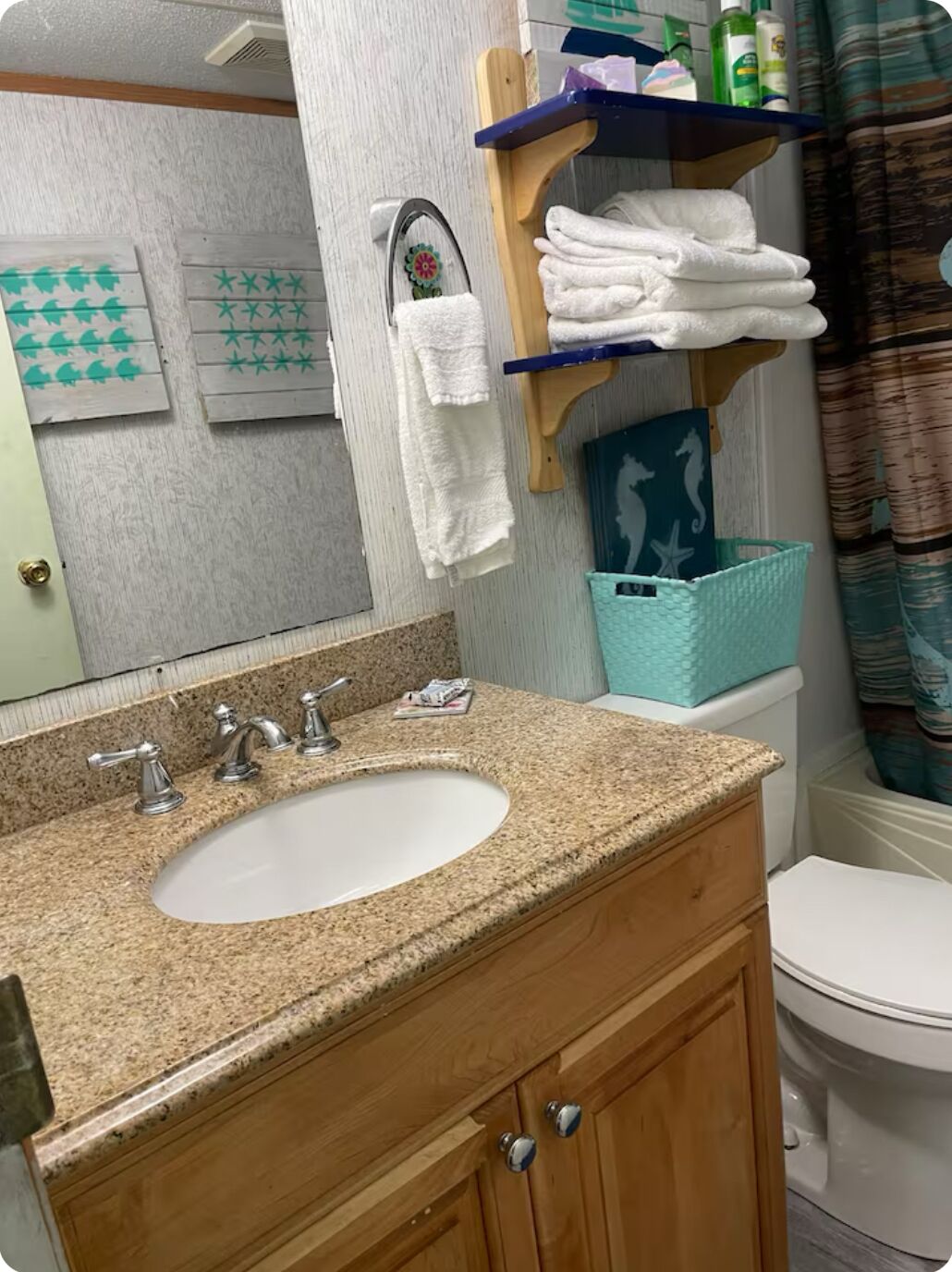 A bathroom with a granite countertop sink, wooden cabinets, a towel rack, and a toilet.
