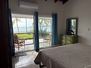 Un dormitorio con cama, cómoda, silla y vista al océano.