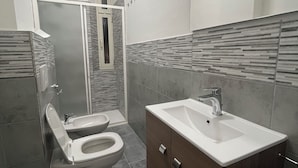 A modern bathroom with a toilet, sink, and shower.