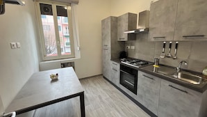 A modern kitchen with grey cabinets, a gas stove, a sink, and a window with blinds.