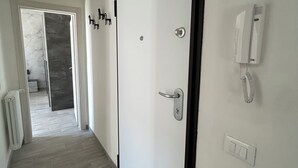 A hallway with a white door, a radiator, a thermostat, a phone, and a light switch.