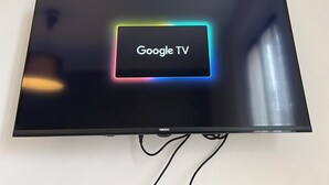 A flat-screen TV with a Google TV interface on a wall.