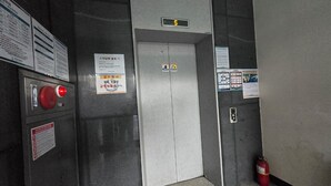 An elevator interior with a digital display showing the number 5, emergency buttons, and informational signs.