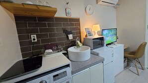 A compact kitchen with a washing machine, a microwave, and a TV.